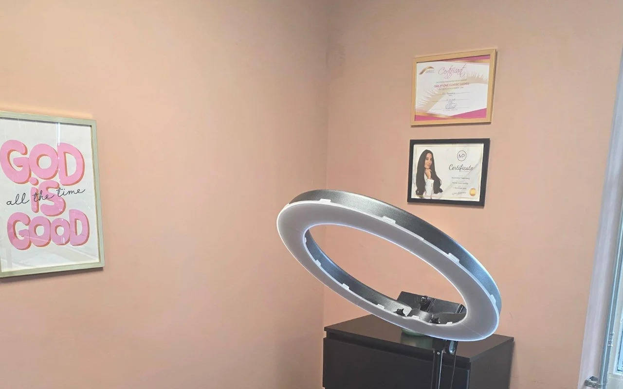 Hoek van de salon met de ringlamp, een roze print en ingelijste certificaten